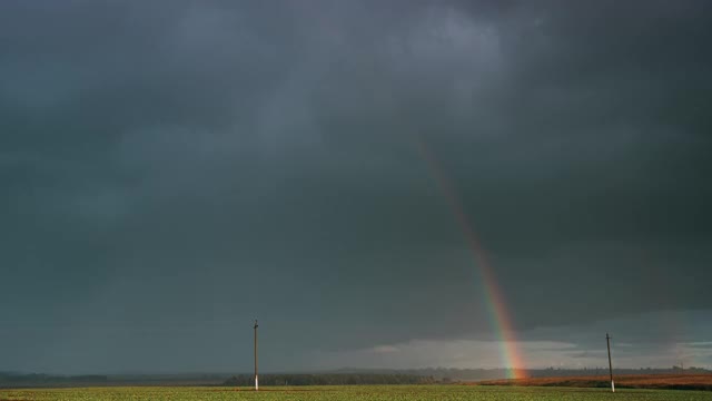 戏剧性的天空在雨与彩虹在地平线上农村景观领域。农业和天气预报概念。时光流逝，时光流逝，时光流逝。秋雨中的乡村草地视频素材