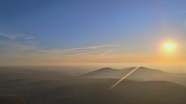 在雄伟的阳光光束下，橙色的夕阳越过山峦景观。视频素材