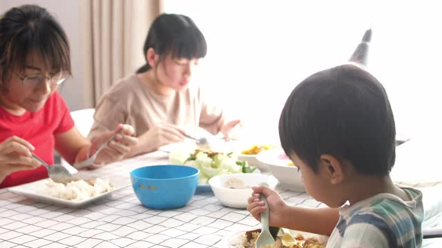 幸福的家庭时间和关系，亚洲家庭在家里一起吃午餐，并在家里的桌子上分享食物视频素材