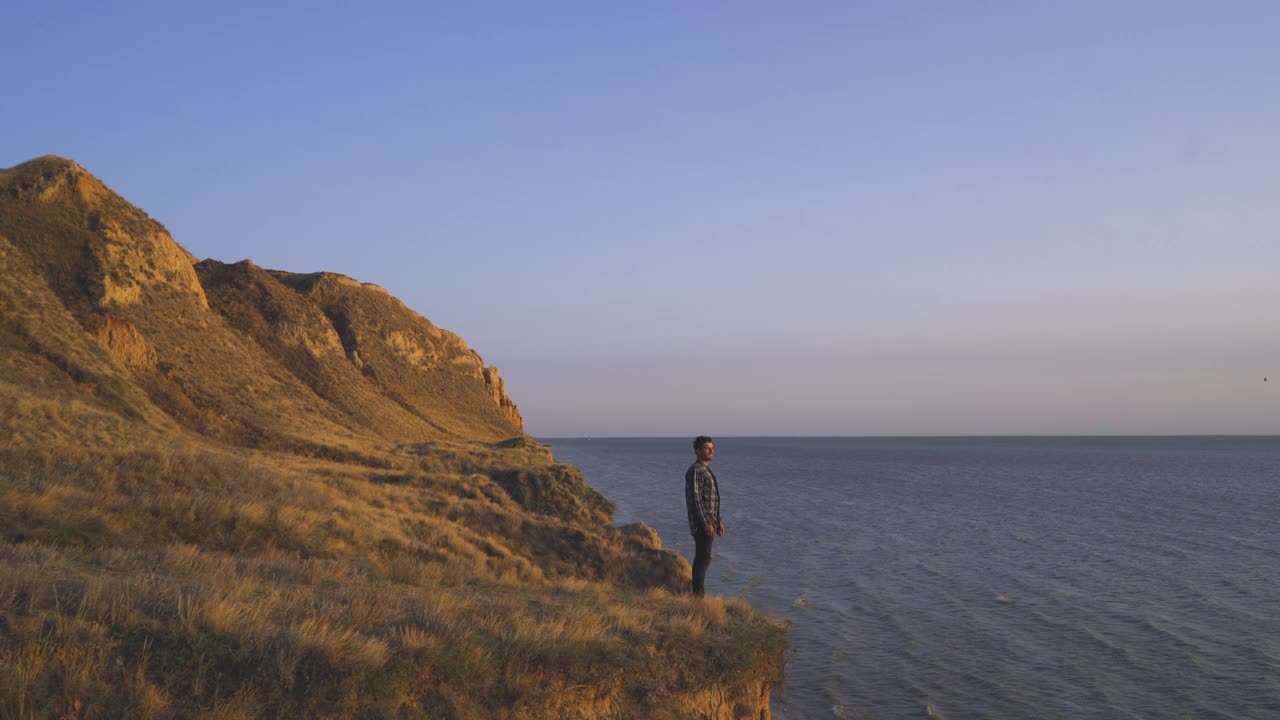 英俊的男人站在山崖上的海景视频素材