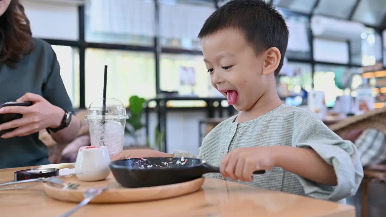 亚洲男孩在咖啡馆里吃着美味的糖果视频下载