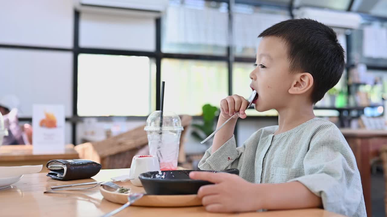 亚洲男孩在咖啡馆里吃着美味的糖果视频下载