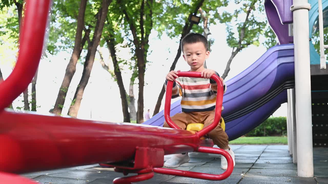 可爱的亚洲男孩在操场上玩得很开心视频下载