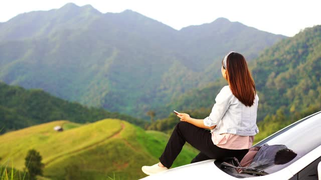 年轻女子坐在车上看美丽的山景，而驾驶公路旅行的假期视频素材