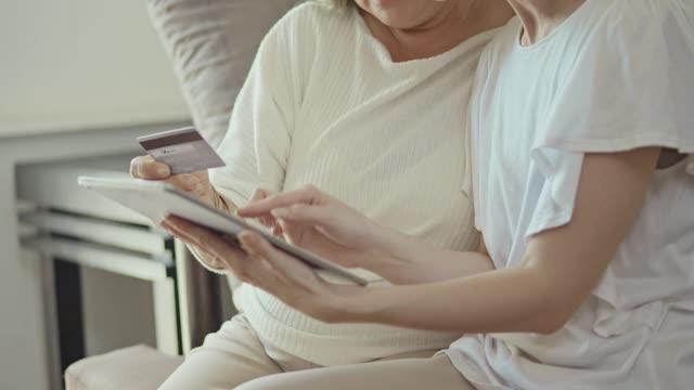 女人和妈妈在家里的数码平板电脑上网购信用卡，慢动作视频素材