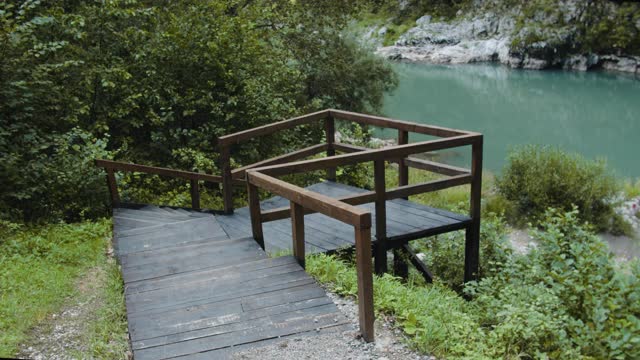 快乐的女游客背着背包跑到山上的湖边。女人举起双手欣赏风景。视频素材