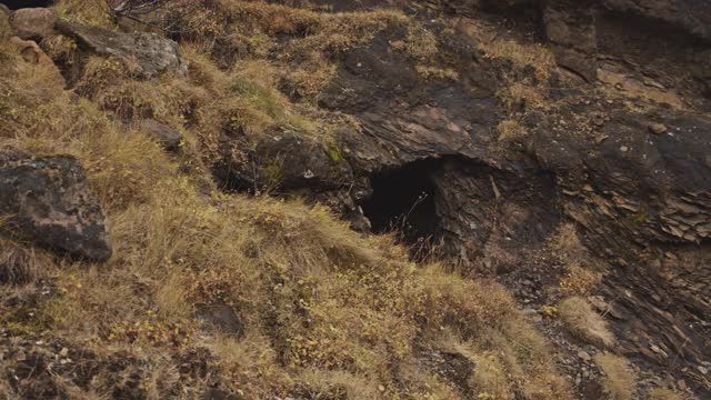 蒙面人和蒙面人离开山坡洞穴视频素材