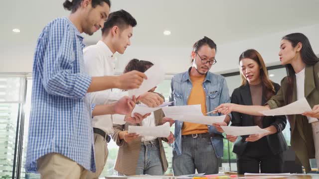 年轻的亚洲商务人士小组在办公室举行讨论会议。男人和女人有交流头脑风暴和共同工作的项目作为团队。现代同事的企业视频素材