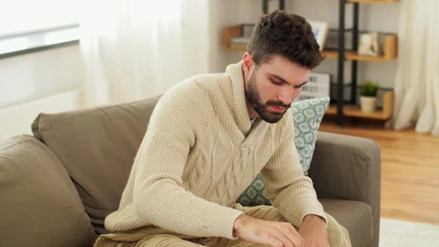 生病的年轻人裹着毯子在家喝热茶视频素材