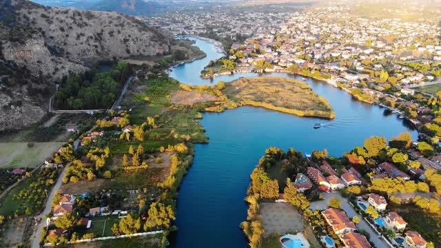 鸟瞰日落时蜿蜒的蓝色河流和小镇。无人驾驶飞机。Dalyan,土耳其,4 k视频下载