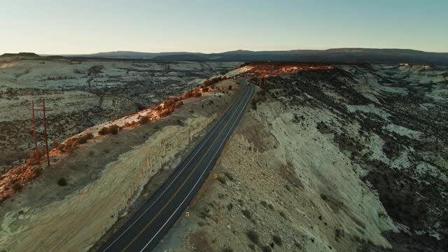 汽车驾驶在孤独的犹他州道路在日出-空中视频素材