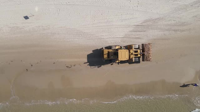 重型机械鸟瞰图，铲装载岩石和砾石在海滩上工作，推土机搬运岩石在海面上工作，重型设备顶部向下进尺视频素材