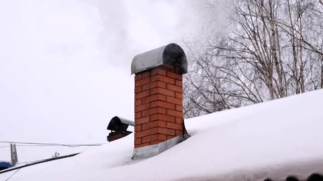 烟从烟囱里冒出来，在取暖。冬天阴天有雪视频素材