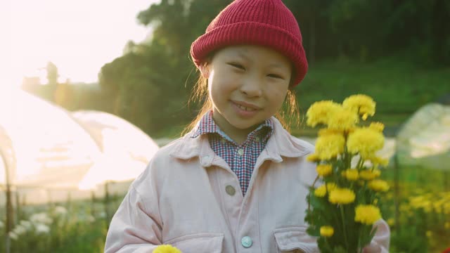 亚洲小孩捧着花在花园农场的背景。4 k慢动作。视频素材