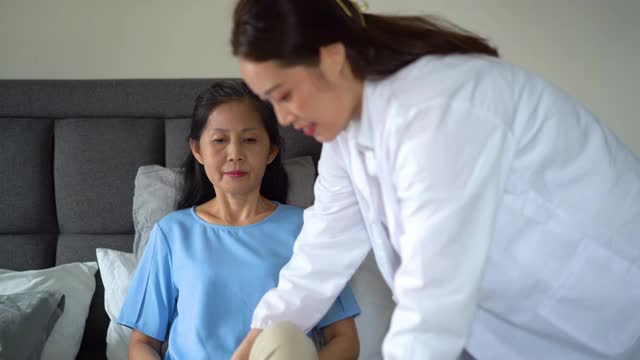 在家中为一名腿伤的老年妇女提供治疗的女性保健工作者视频素材