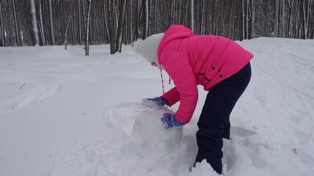 小女孩在冬天的森林里堆雪人视频素材