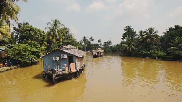 印度喀拉拉邦回水区，在棕榈树附近的河流上漂浮的船屋视频素材