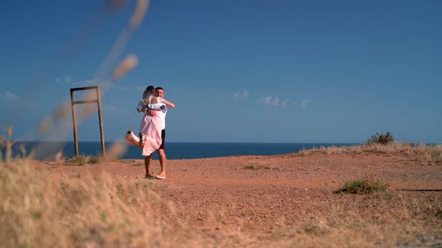 一对新婚夫妇，一对年轻的夫妇在海边浪漫的相遇，互相拥抱，慢镜头拍摄。蜜月。视频素材