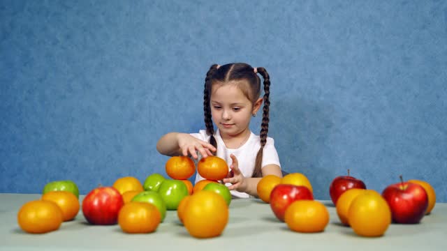 可爱的小女孩在家吃水果。小孩正在桌子上堆水果。有机健康食品的快乐孩子视频素材