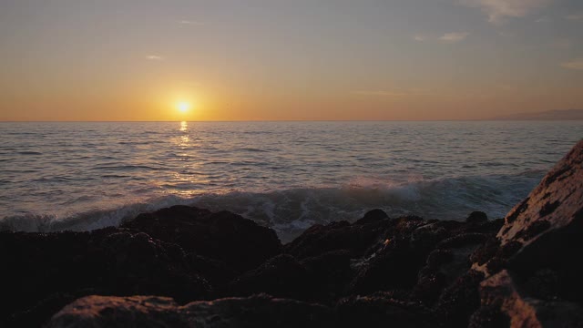 巨大的海洋日落。燃烧的天空，金色的海浪拍打着岩石。日落海4 k。海鸥在飞翔。红色的天空，黄色的太阳和惊人的海洋。夏日夕阳海景。缓慢的运动。视频素材