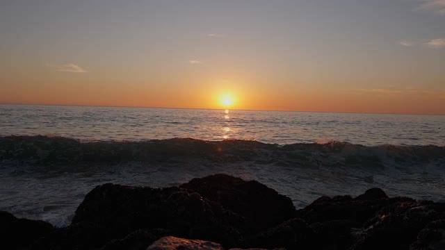 巨大的海洋日落。燃烧的天空，金色的海浪拍打着岩石。日落海4 k。海鸥在飞翔。红色的天空，黄色的太阳和惊人的海洋。夏日夕阳海景。缓慢的运动。视频素材