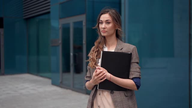 女商人成功的女商人站在户外公司大楼的外部。沉思的白人自信职业女性中年视频素材