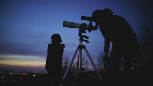 母女俩用天文望远镜观察星星、行星、月亮和夜空。视频素材