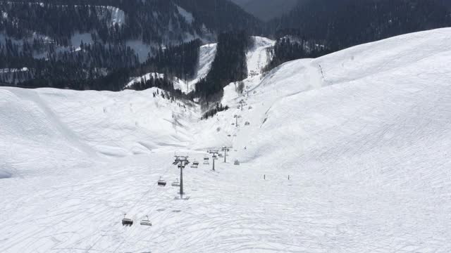 鸟瞰图上翻索道高山滑雪胜地与惊人的自然山地景观。从直升机索道拍摄的丘陵地形周围的雪冬季视频素材