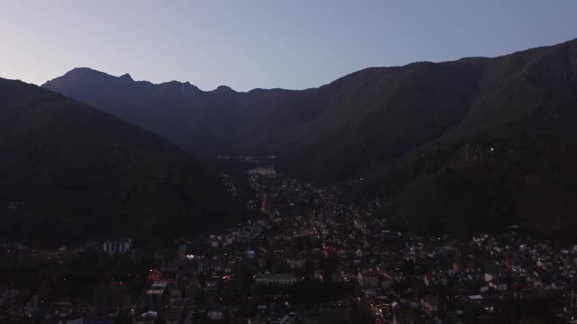 从空中俯瞰阿奇什科山风景中夜晚的旅游村庄。黑暗的城市景观在红杉波利亚纳度假村建筑在自然岩石形成的风景视频素材