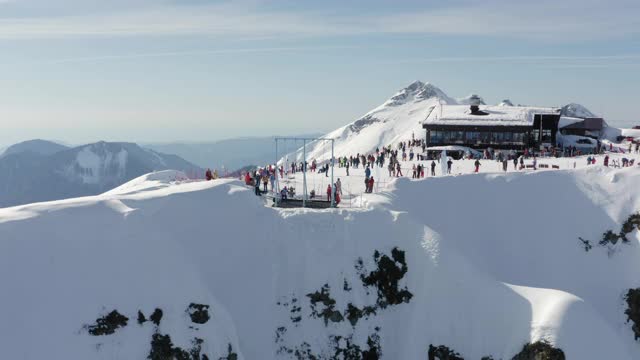 活跃的人们在高山滑雪胜地的2320峰消磨时间。享受极端冒险生活方式的人在滑雪和滑雪板中心反向鸟瞰图在阳光明媚的冬日视频素材