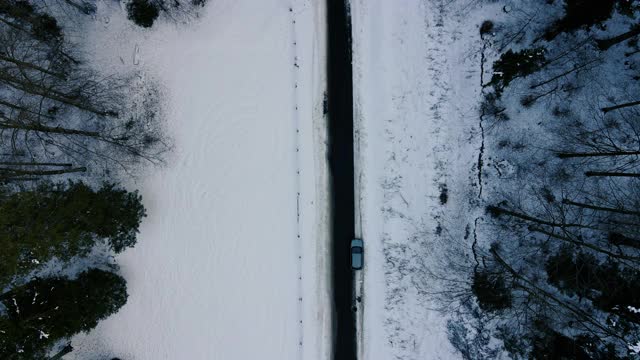 从鸟瞰图向上倾斜穿过雪域森林的乡村道路视频素材