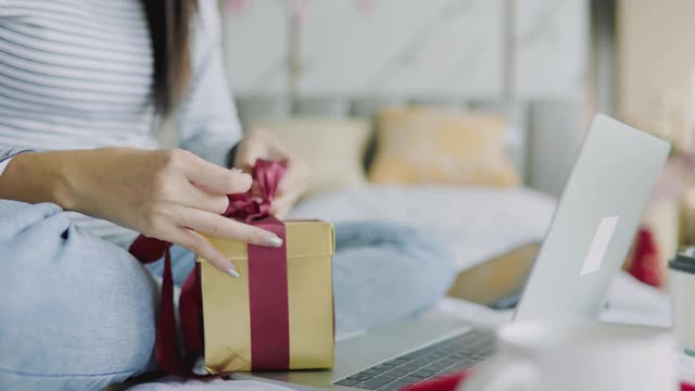 女人在家里收到了一份圣诞礼物。兴奋的女人拿着圣诞礼物。亚洲妇女倒数并通过视频电话会议庆祝新年派对。视频素材