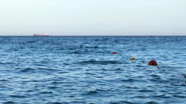 海中游泳区的浮栅栏，设浮标。在蓝水上用浮标标记区域。游泳区边界标志。视频素材