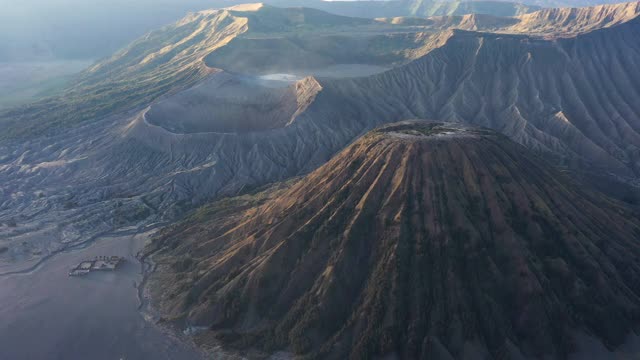 从上面俯瞰，令人惊叹的巴托克山和布罗莫山的巨大火山口在阳光明媚的一天被照亮。布罗莫火山是印度尼西亚东爪哇的一座活火山。视频素材