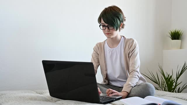 远程学习在线教育。十几岁的女学生使用笔记本电脑在家学习视频素材