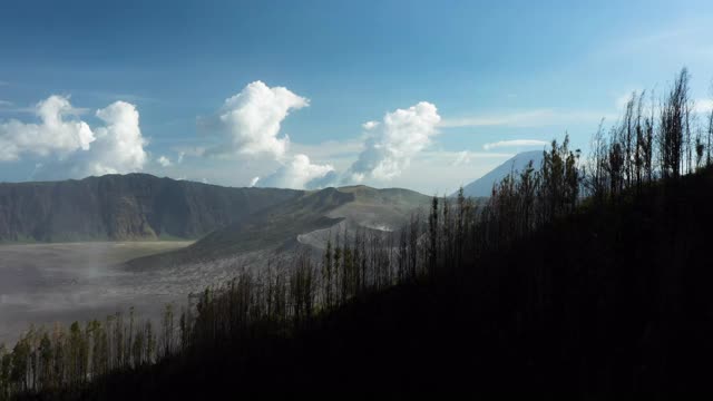 从上面俯瞰，令人惊叹的巴托克山和布罗莫山的巨大火山口在阳光明媚的一天被照亮。布罗莫火山是印度尼西亚东爪哇的一座活火山。视频素材