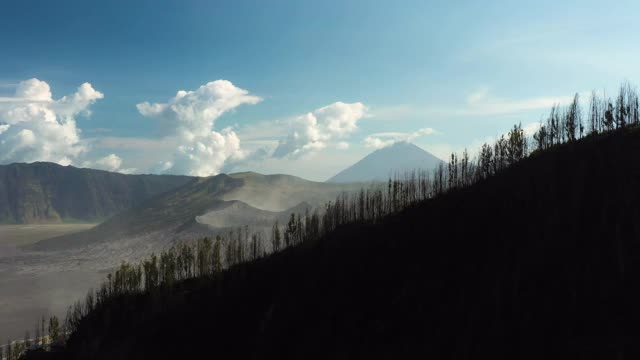 从上面俯瞰，令人惊叹的巴托克山和布罗莫山的巨大火山口在阳光明媚的一天被照亮。布罗莫火山是印度尼西亚东爪哇的一座活火山。视频素材