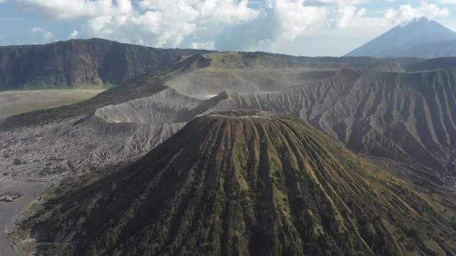 从上面俯瞰，令人惊叹的巴托克山和布罗莫山的巨大火山口在阳光明媚的一天被照亮。布罗莫火山是印度尼西亚东爪哇的一座活火山。视频素材