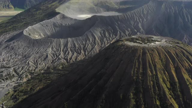 从上面俯瞰，令人惊叹的巴托克山和布罗莫山的巨大火山口在阳光明媚的一天被照亮。布罗莫火山是印度尼西亚东爪哇的一座活火山。视频素材