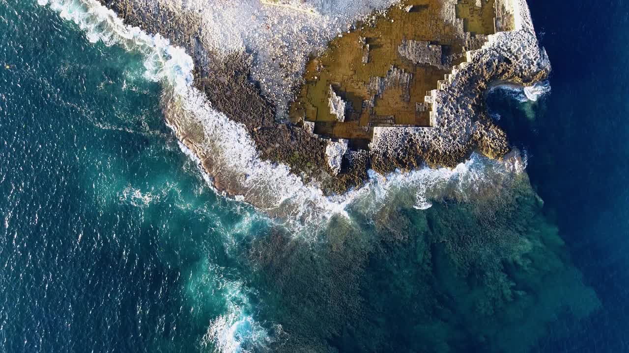 地中海梅诺卡岛的珊瑚礁和海岸线。我们可以看到海浪在礁石上翻滚，产生4K的泡沫视频素材