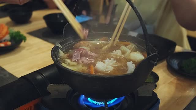 一家人在日本餐馆吃涮涮锅晚餐。和家人一起吃涮锅饭。视频素材