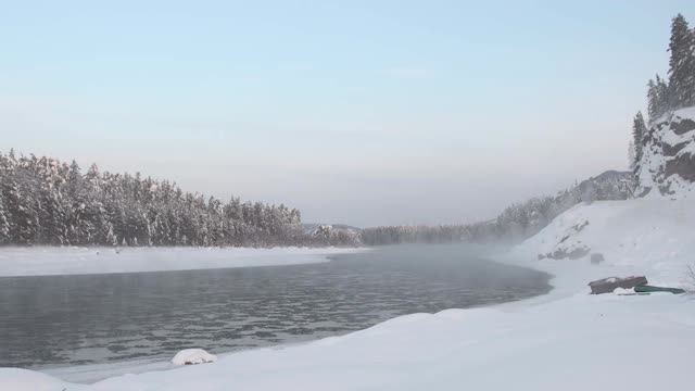 多雾的河和浮冰。冬天的景色有雪林和岸边翻船。视频素材