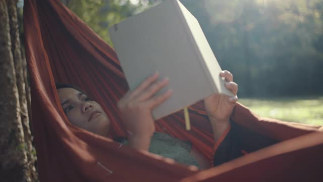 一个在吊床上看书的女人视频素材