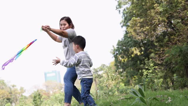 亚洲母亲和儿子在花园公园放风筝视频素材