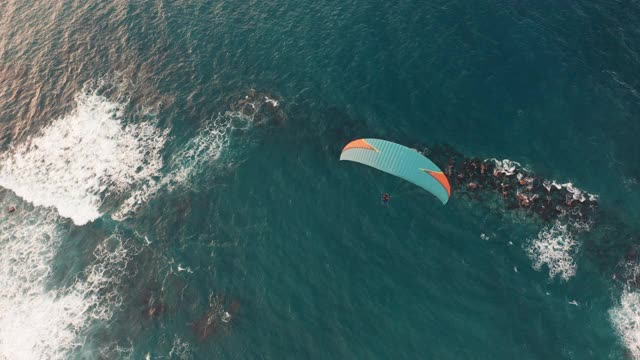 鸟瞰图。降落伞在风景如画的海滩上空飞行视频素材