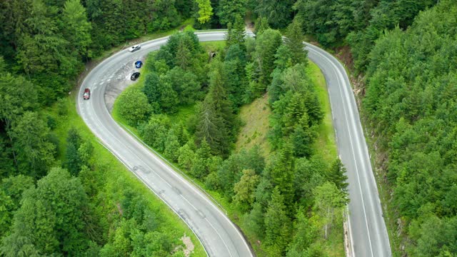 从空中望去，柴油车和汽车在树木环绕的山区道路上行驶。视频素材