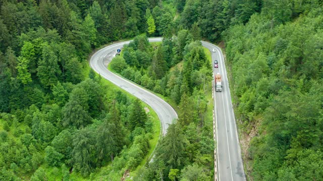 鸟瞰图景观弯曲的道路与移动的柴火卡车在山上高绿树视频素材