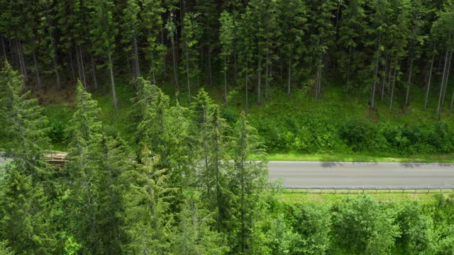 从空中望去，柴油车和汽车在树木环绕的山区道路上行驶。视频素材