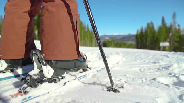 特写:滑雪者将雪板上的雪踢向空中，然后开始滑下斜坡视频素材