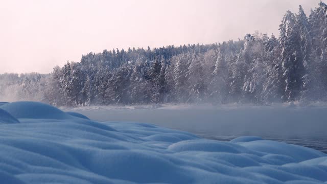 河面结冰，水面开阔，岸上有雪堆。多云多雾的冬日视频素材